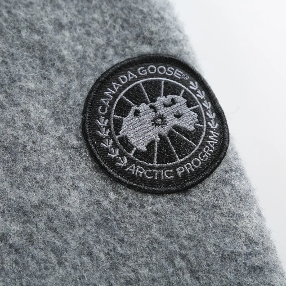 P780 Canada Goose Fleece Badge Hooded Jacket Fabric selection: Wool fleece fabric blended with wool as the main body and a very small amount of spandex and polyester fibers. Wool is a core natural ingredient that provides unparalleled temperature regulation, antibacterial and anti-odor properties and a skin-friendly feel. The feeding of a small amount of spandex gives the fabric a certain degree of four-way elasticity, making it non-restrictive during daily activities. As the basis of fleece's structure, polyester fiber enhances the fabric's durability, wrinkle resistance and quick-drying properties. It contributes to the loft of the fleece and provides functions such as trapping air.  Detail 1: The sleeves and hem are closed with 2×2 ribbing. Its strong elasticity can closely fit wrists and waists of different thicknesses, forming an effective 'seal' to prevent cold wind from blowing back. It can still maintain its original shape after repeated stretching and use, and is not easy to loose and deform. And the ribbed cuffs can convey a sense of design and enhance the visual beauty.  Detail 2: The combination of hood design and elastic buckle improves warmth and windproof performance when wearing.  Accessories: 1:1 customized elastic drawstring buckle, 1:1 customized zipper pendant, 1:1 customized armband SIZE: S M L XL